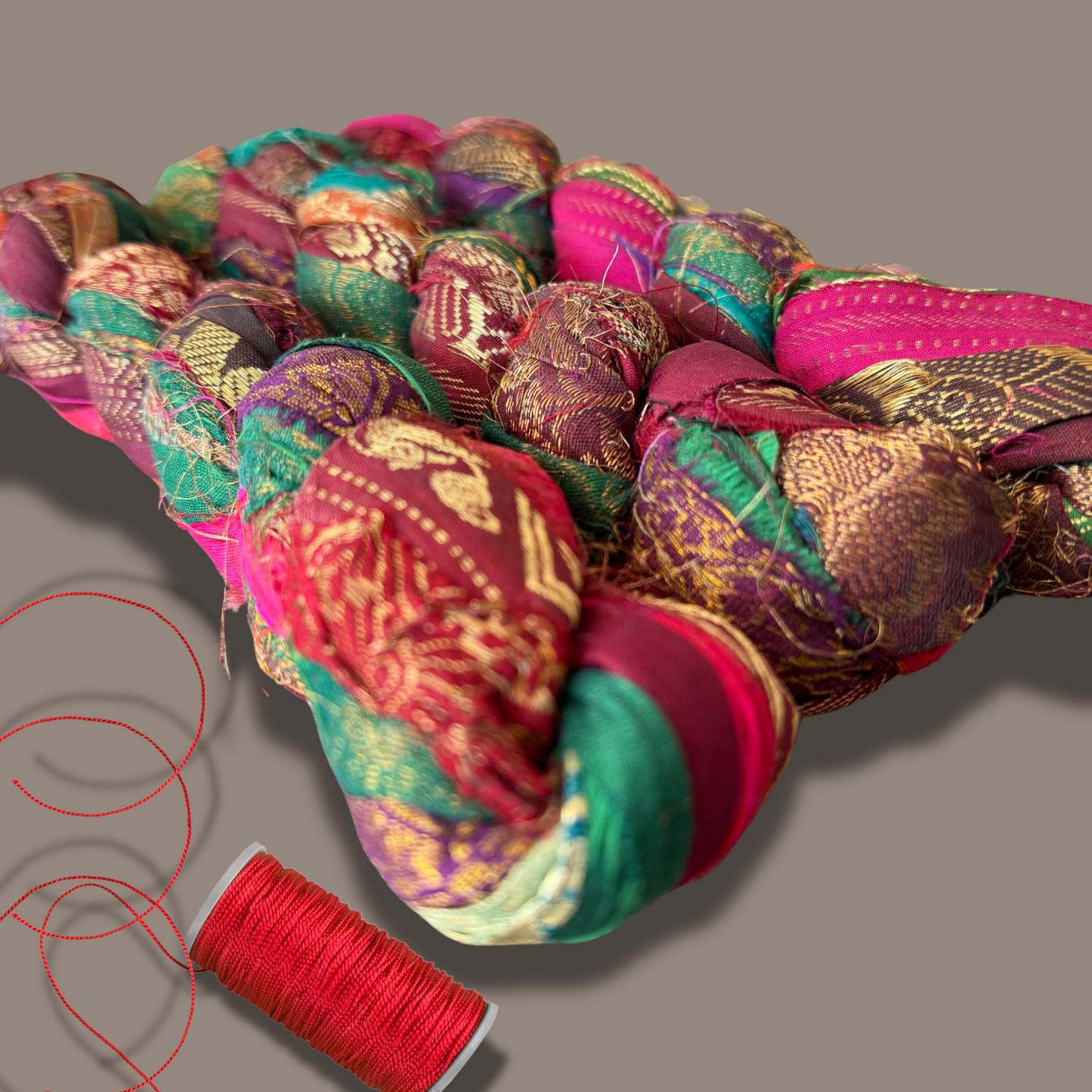 Bohemian Silk Ribbon on a grey background with a spool of red thread on the side