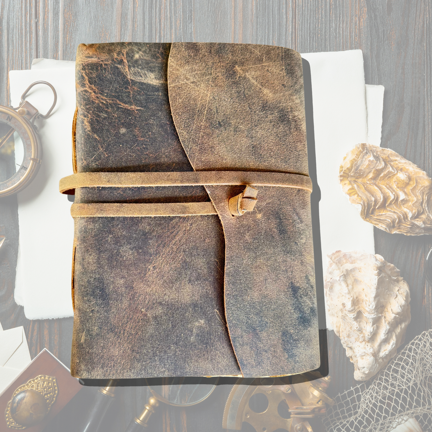 Delaney Leather Sketchbook on an asthetic background with antique looking pen, magnifying glass, stone, clock etc in the background.