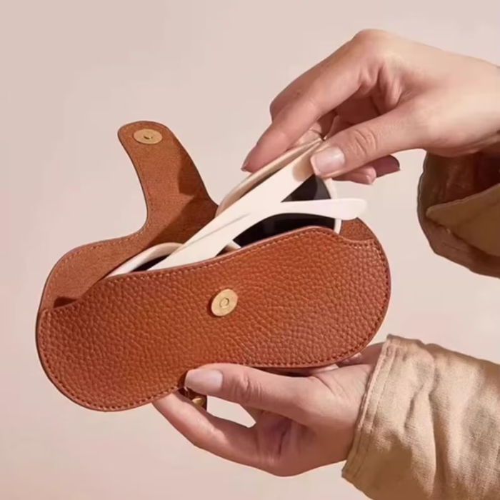 A woman putting her sunnies in her brown Glasses case