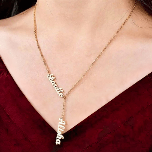 A woman wearing a personalised necklace in gold with 2 names Sharelle and Alisha.