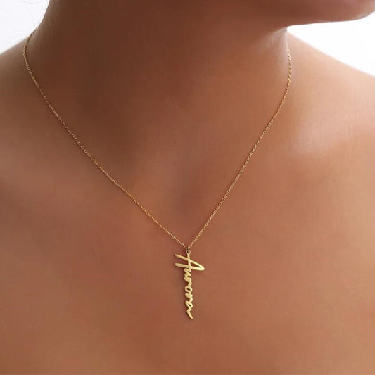 A woman wearing the Cassia Signature Necklace in gold with the name Aurora.