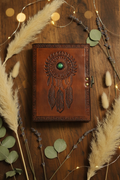 Leather dream catcher journal cover with green eye and feather embossing, side clasp.