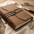 Handmade leather journal with gold embossed name, tied with leather strap, styled on linen with fountain pen and dried flowers – personalised leather journal Australia