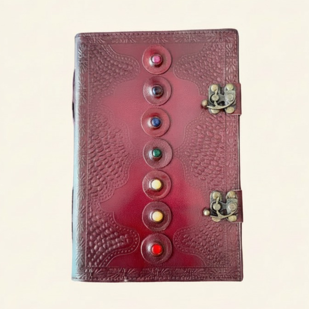Red leather journal with embossed design and colorful stones on a light background