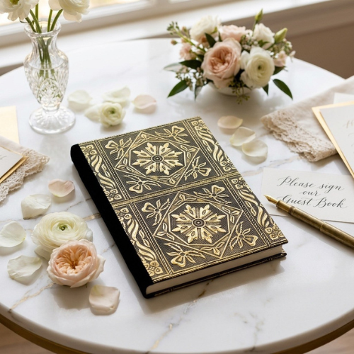 Wedding guest book angled view, dark cover with gold geometric floral medallions.