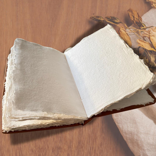 Handmade colouring book on a wooden table with brown dried leaves on the side