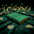 Green embossed leather sketchbook with patterned cover, lying on a cloth