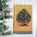Handmade notebook on a white background with tree leaves on the side
