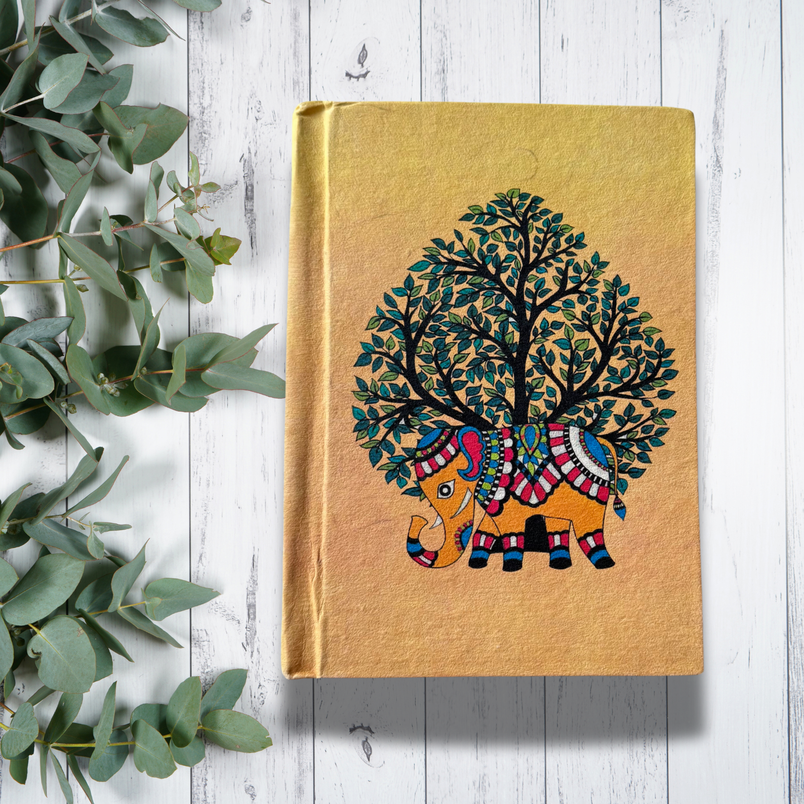 Handmade notebook on a white background with tree leaves on the side
