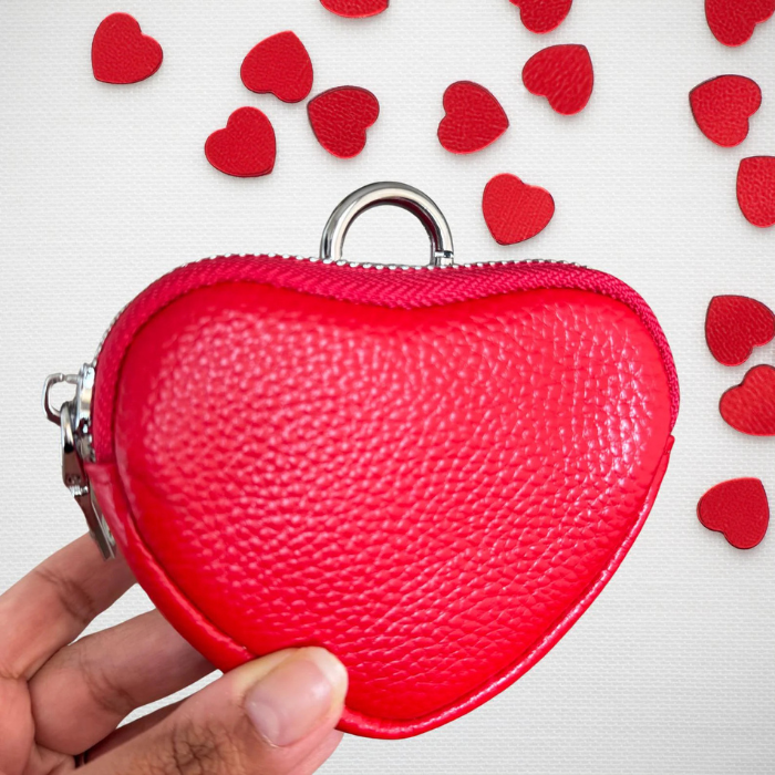 Red heart coin purse held in hand with metal keyring and pebbled texture