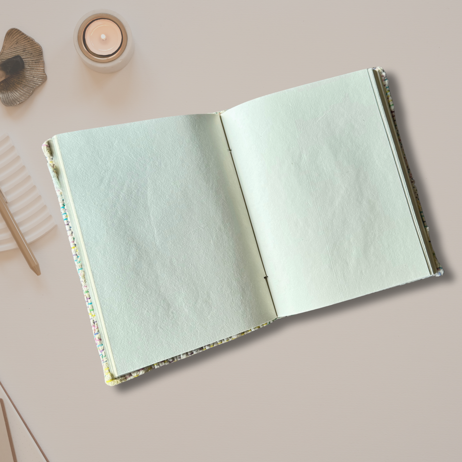 Open silk yarn notbook on an asthetic background with a candle burning on the side
