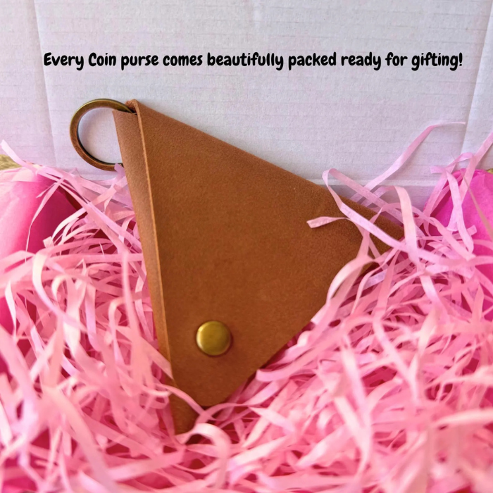 Tan triangle coin purse in pink shredded gift filler with gold-tone snap button.