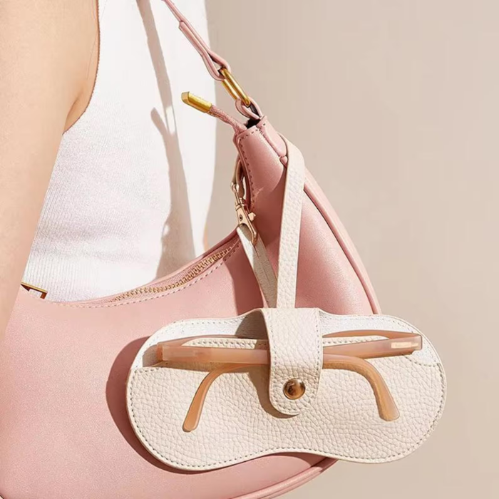 A woman holding a bag with her sunglasses case hanging on her bag
