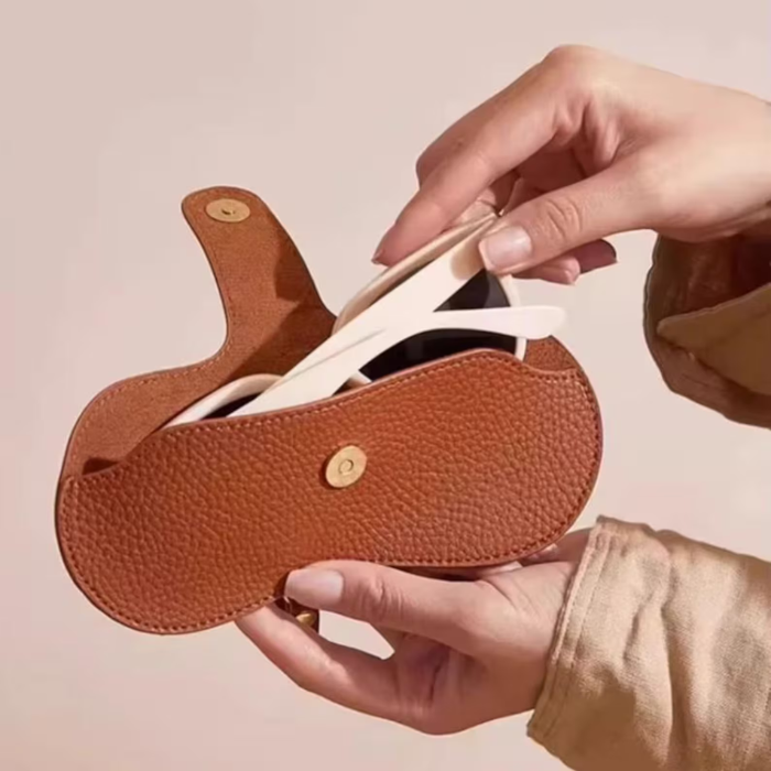 a woman putting her sunnies in her brown sunglass case
