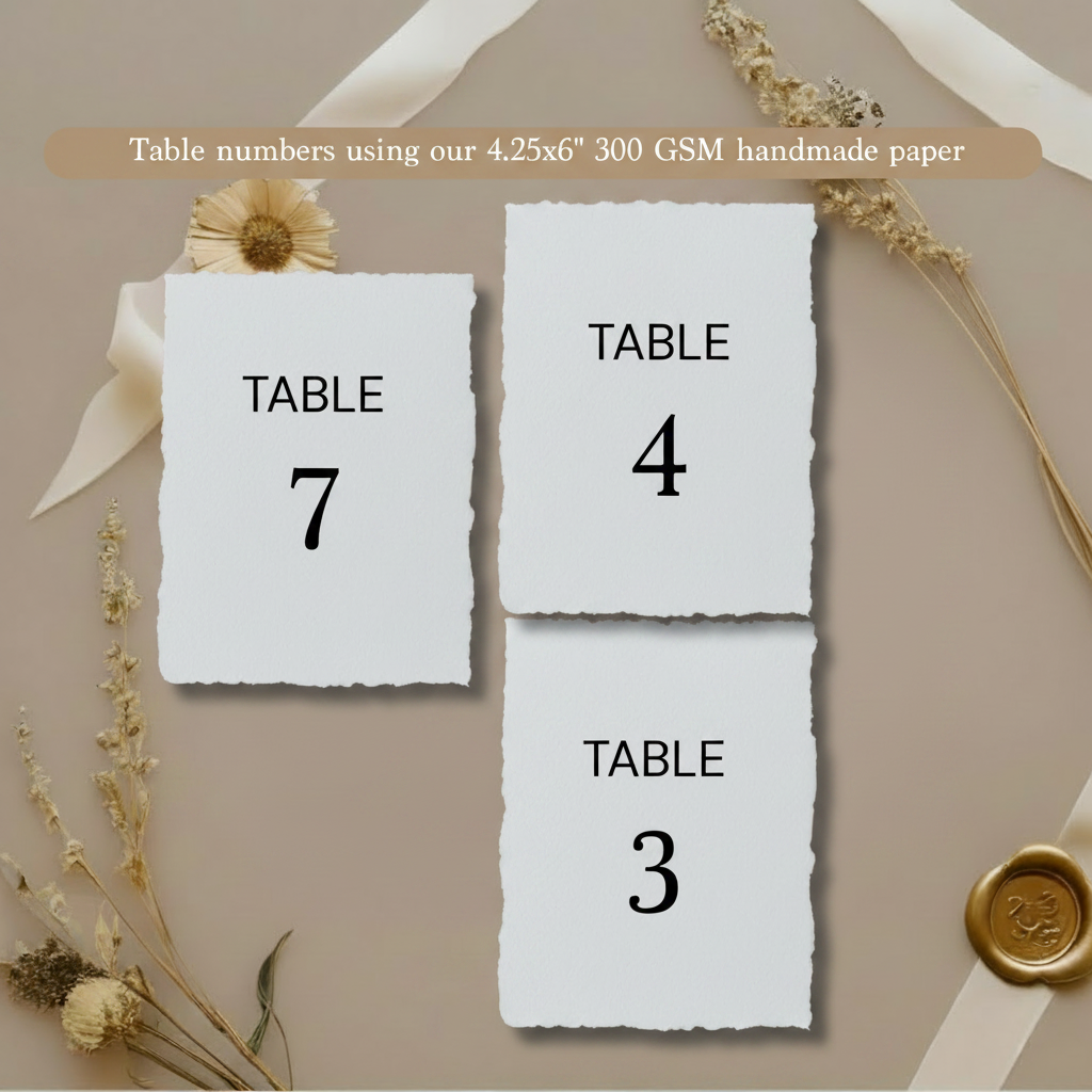 Three wedding table number cards (Table 3, 4 and 7) printed on white 300 GSM handmade cotton rag paper 4.25x6 inch with natural deckle edges, styled with dried flowers and gold wax seal on taupe background