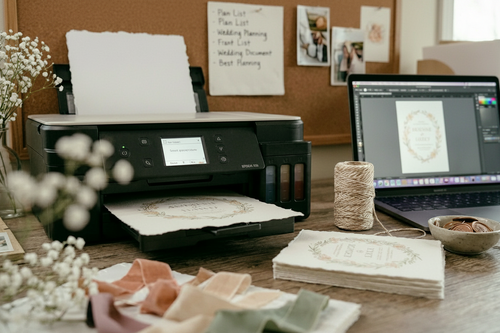Printing DIY wedding invitations on handmade deckle edge cotton rag paper using an Epson printer with twine and stationery flat lay.